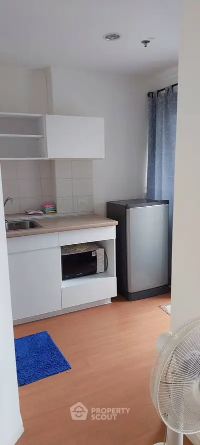 Compact kitchen with modern appliances and wooden flooring in cozy apartment
