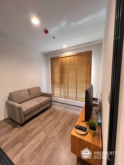 Cozy living room with modern wooden flooring, comfortable sofa, and warm lighting, perfect for relaxation and entertainment.