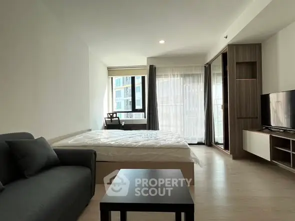 Modern studio apartment with cozy living area and large windows for natural light.