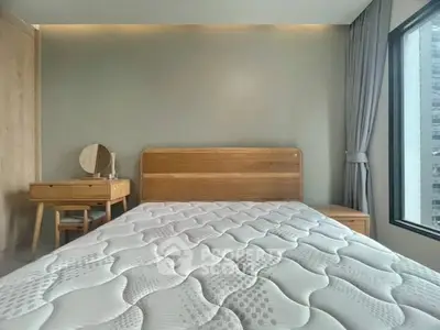 Modern bedroom with wooden furniture and large window view.
