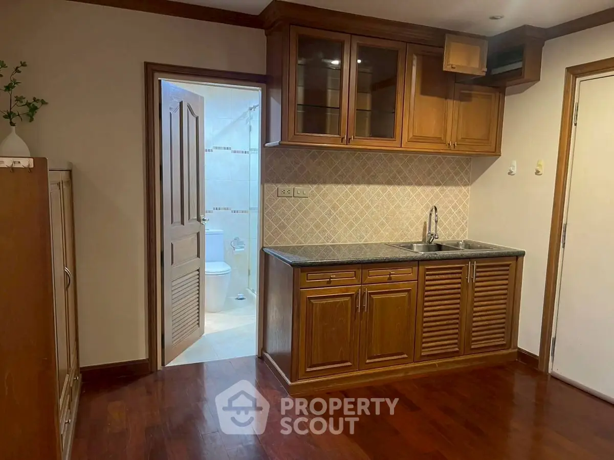 Cozy kitchen with wooden cabinets and adjacent bathroom in a charming home.