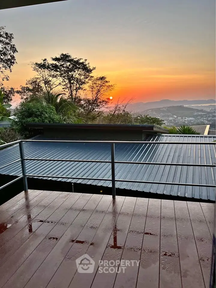 Stunning sunset view from a spacious balcony overlooking lush greenery and cityscape.