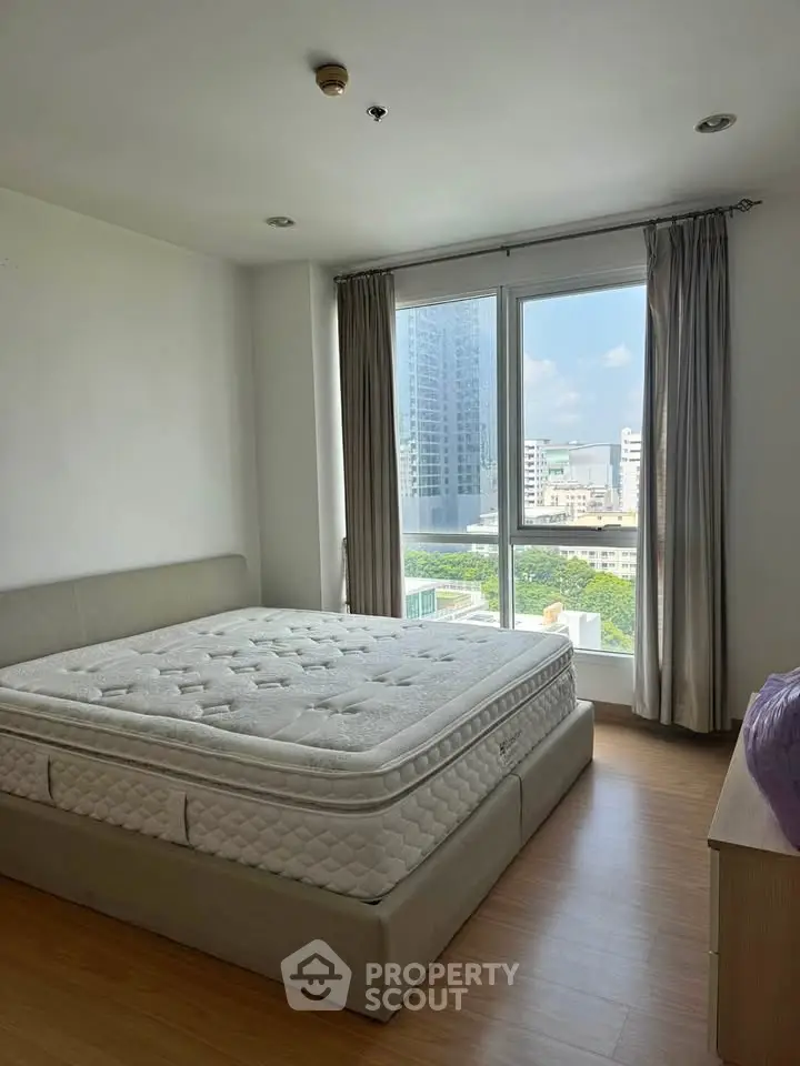 Spacious bedroom with large window offering city views and natural light.