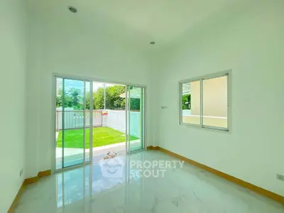 Bright empty room with large sliding glass doors leading to a lush green garden, perfect for natural light lovers.
