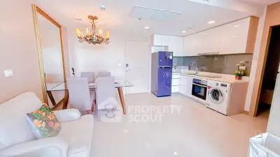 Modern open-layout living room with dining area, featuring sleek kitchen appliances and elegant decor.