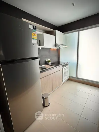Modern kitchen with stainless steel fridge and sleek cabinetry in a bright apartment.