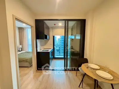Modern apartment interior with open kitchen and cozy dining area, featuring a view of the city skyline.