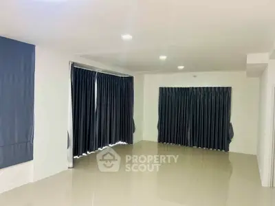 Spacious unfurnished living room with large windows and elegant curtains, perfect for customization.