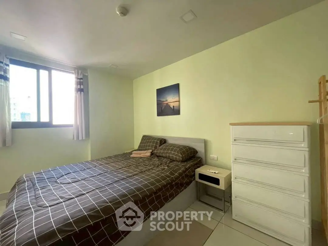 Cozy bedroom with natural light and modern furnishings in a serene apartment setting.