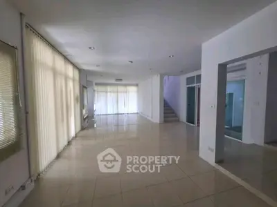 Spacious open-plan living area with large windows and modern tile flooring