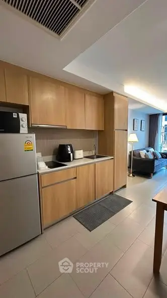 Modern kitchen with wooden cabinets and stainless steel appliances in open layout apartment.