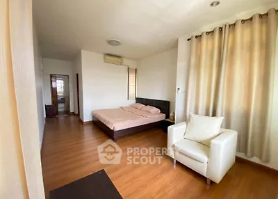 Spacious bedroom with wooden flooring and cozy furnishings for a comfortable living experience.