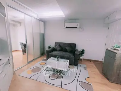 Cozy living room with modern sofa, glass coffee table, and stylish decor in a compact space.