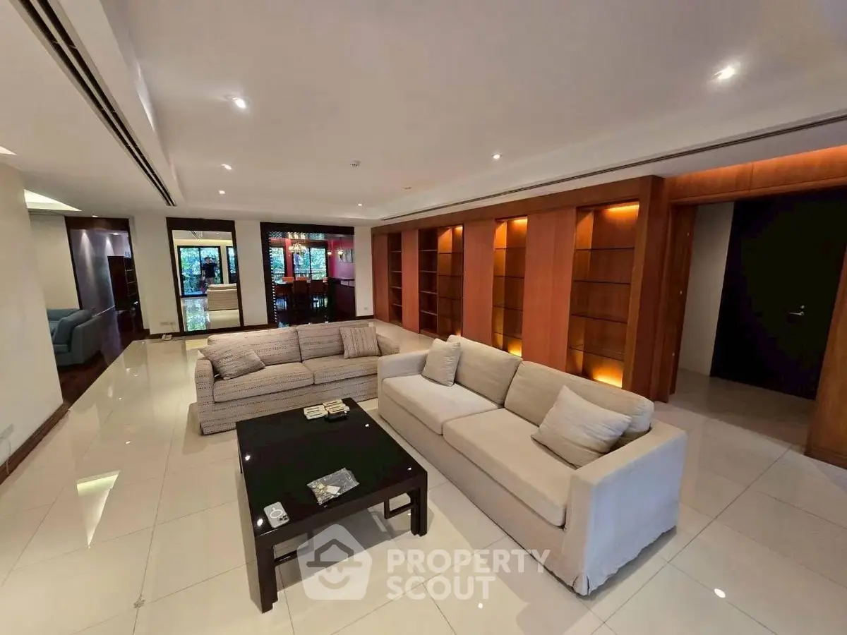 Spacious modern living room with elegant sofas and built-in wooden shelves.