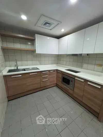 Modern kitchen with sleek cabinetry and built-in appliances in a cozy corner layout.