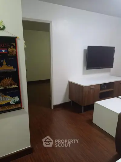 Modern living room with wall-mounted TV and stylish wooden flooring.