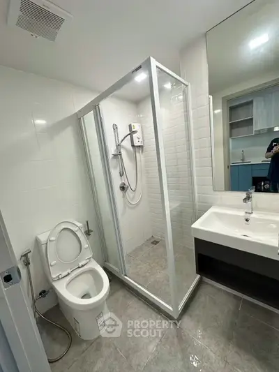Modern bathroom with glass shower enclosure and sleek fixtures in a contemporary apartment.