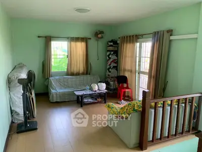 Cozy living room with natural light, wooden flooring, and simple furnishings for a comfortable home atmosphere.