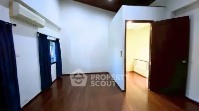 Spacious empty room with wooden flooring and air conditioning, ideal for customization.