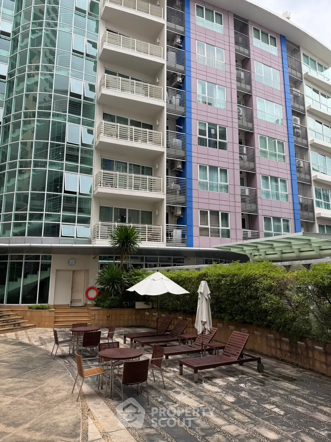 Modern apartment building with outdoor seating area and lush greenery