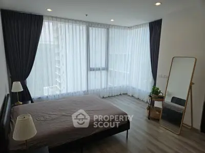 Spacious bedroom with large windows and modern decor in a high-rise apartment.