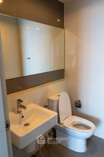 Modern bathroom with sleek fixtures and large mirror in contemporary apartment.