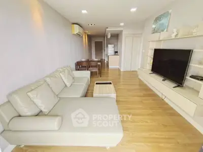 Spacious living room with modern decor and open layout, featuring a large TV and comfortable seating.