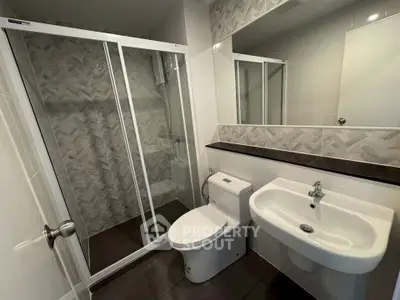 Modern bathroom with sleek shower and stylish sink in contemporary apartment.