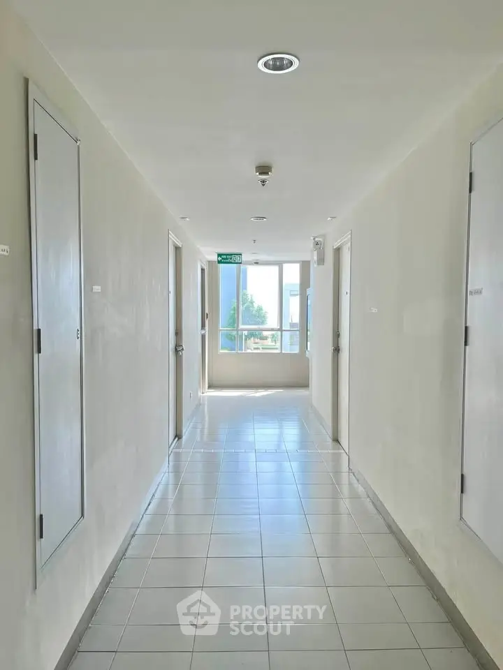 Bright and clean apartment corridor with tiled flooring and natural light.