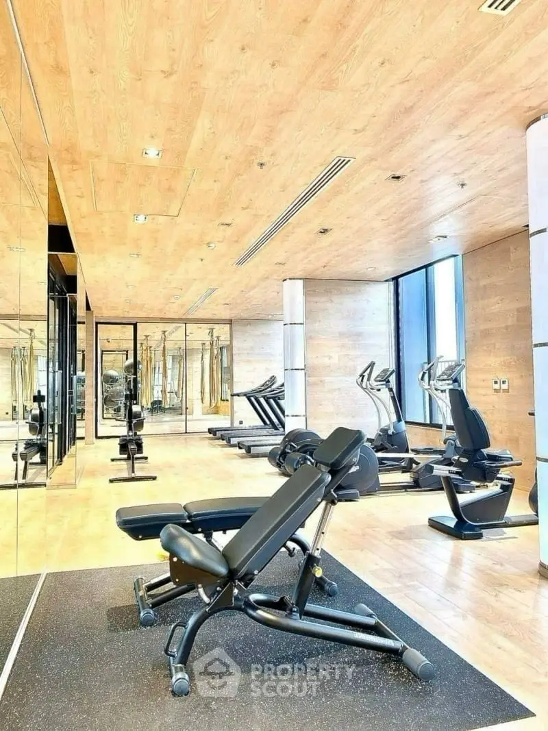 Modern gym with state-of-the-art equipment and mirrored walls in luxury building.