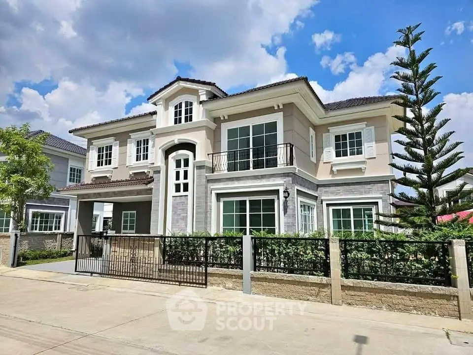 Luxurious two-story house with modern design and lush landscaping under a clear blue sky.