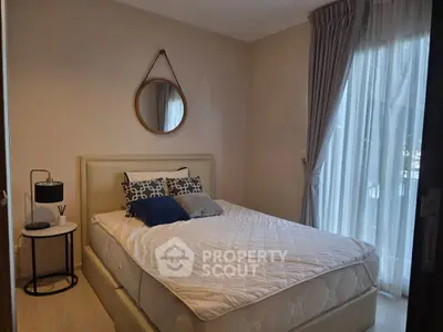 Cozy bedroom with stylish decor and natural light through large window.