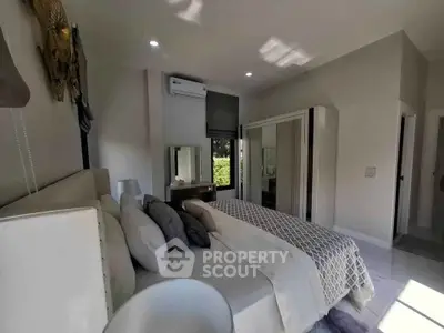 Luxurious bedroom with modern decor and ample natural light, featuring a stylish bed and mirrored wardrobe.