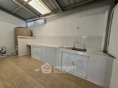Spacious utility area with tiled countertop and dual sinks, perfect for laundry or storage needs.