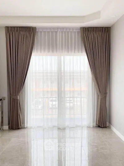 Elegant living room with floor-to-ceiling windows and luxurious curtains, offering a bright and airy ambiance.