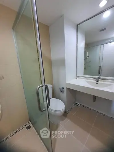 Modern bathroom with glass shower and sleek fixtures in a contemporary apartment.