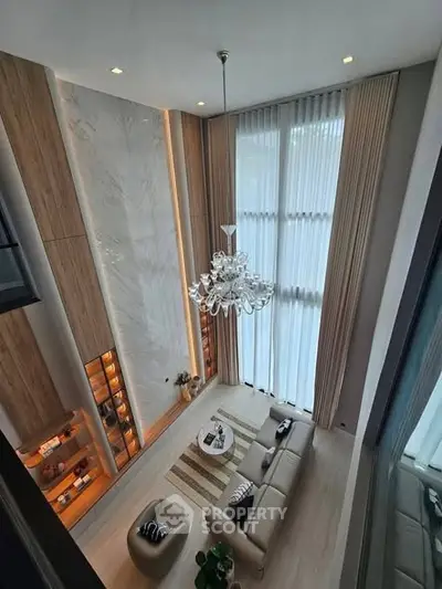 Luxurious high-ceiling living room with elegant chandelier and floor-to-ceiling windows