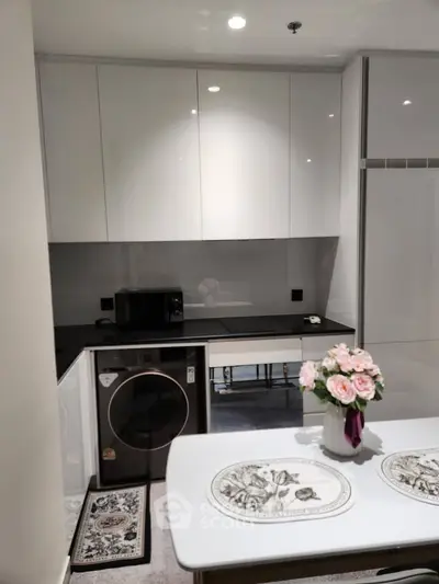 Modern kitchen with sleek cabinets, washing machine, and elegant dining setup.