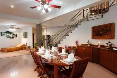 Elegant dining area with wooden table, stylish decor, and modern lighting in a spacious open-plan living room.