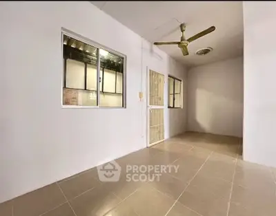 Spacious interior with tiled flooring and ceiling fan, perfect for versatile living space.