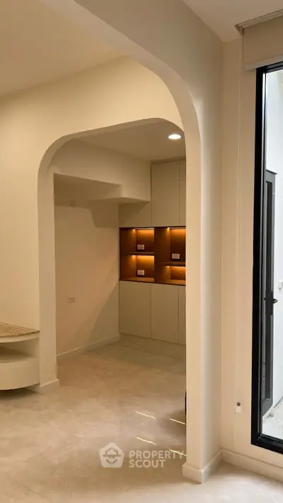 Modern interior with elegant archway and built-in shelving, featuring sleek design and natural lighting.