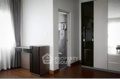 Modern bedroom with sleek wardrobe and natural light from large window.