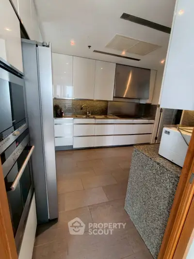 Modern kitchen with sleek white cabinets and stainless steel appliances in a luxury apartment.