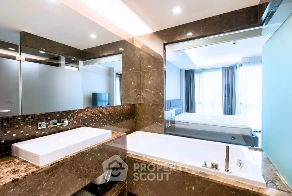 Luxurious bathroom with marble finishes and a view into a modern bedroom.