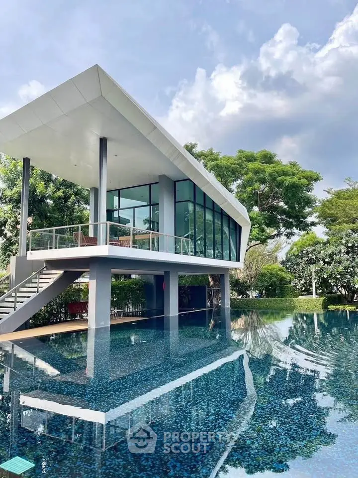 Stunning modern house with glass facade overlooking a serene pool and lush greenery, perfect for luxury living.