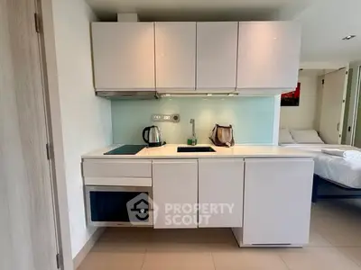 Modern compact kitchen with sleek white cabinets and built-in appliances in a stylish apartment.