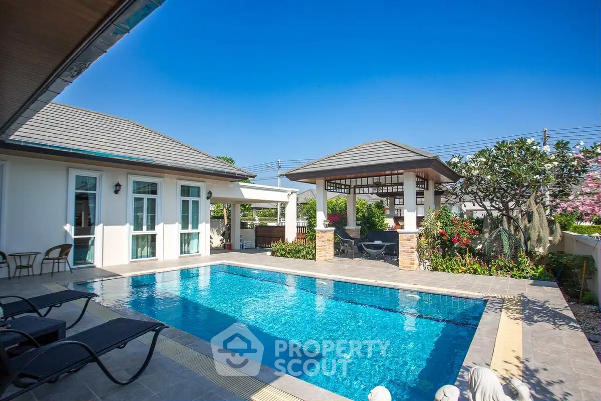 Luxurious villa with private pool and lush garden under clear blue sky.