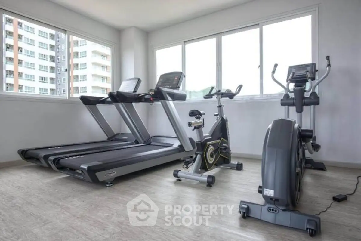 Modern gym with treadmills and exercise bike in bright room with large windows.