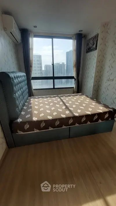 Spacious bedroom with large window offering city views and stylish decor.