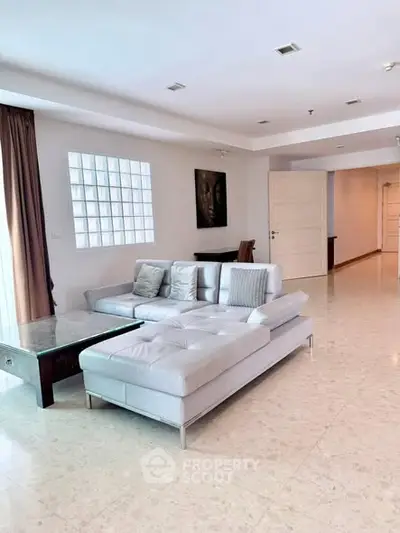 Spacious living room with modern white sectional sofa and marble flooring